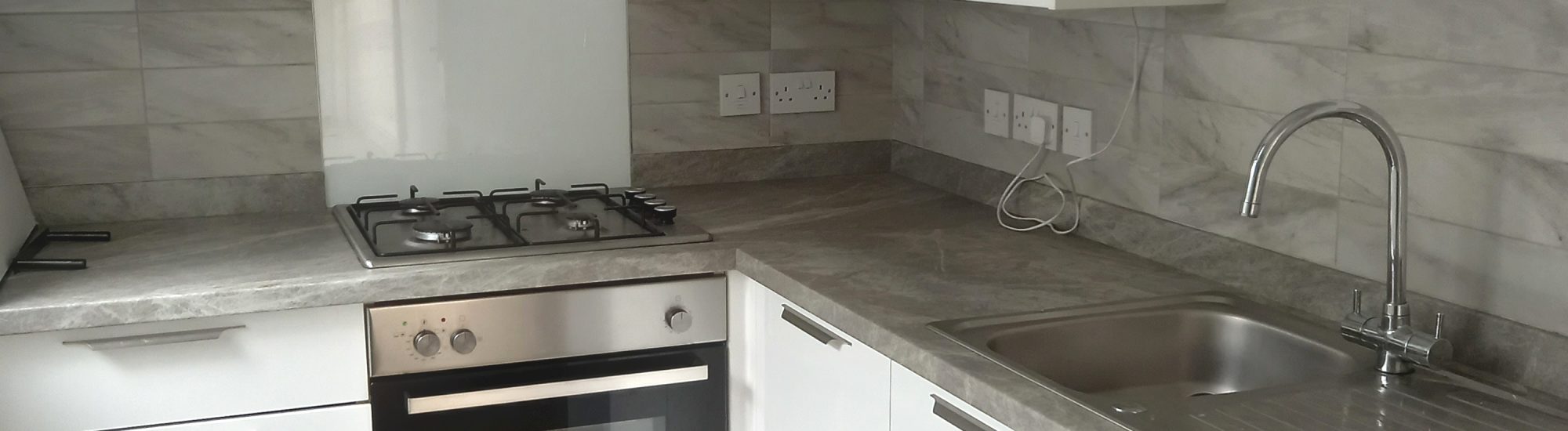 Fitted kitchen with white units and dark grey worktops