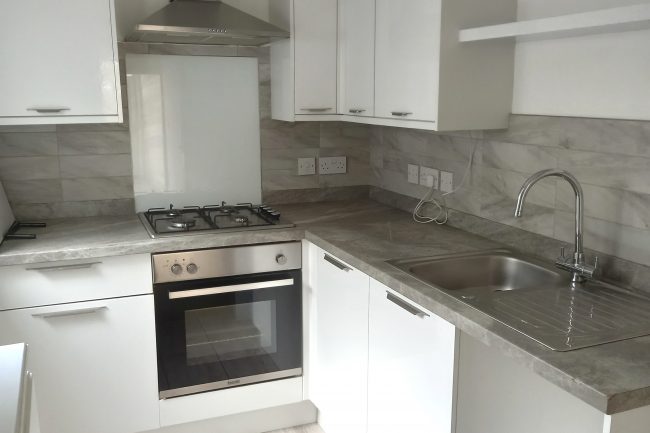 Fitted kitchen with white units and dark grey worktops
